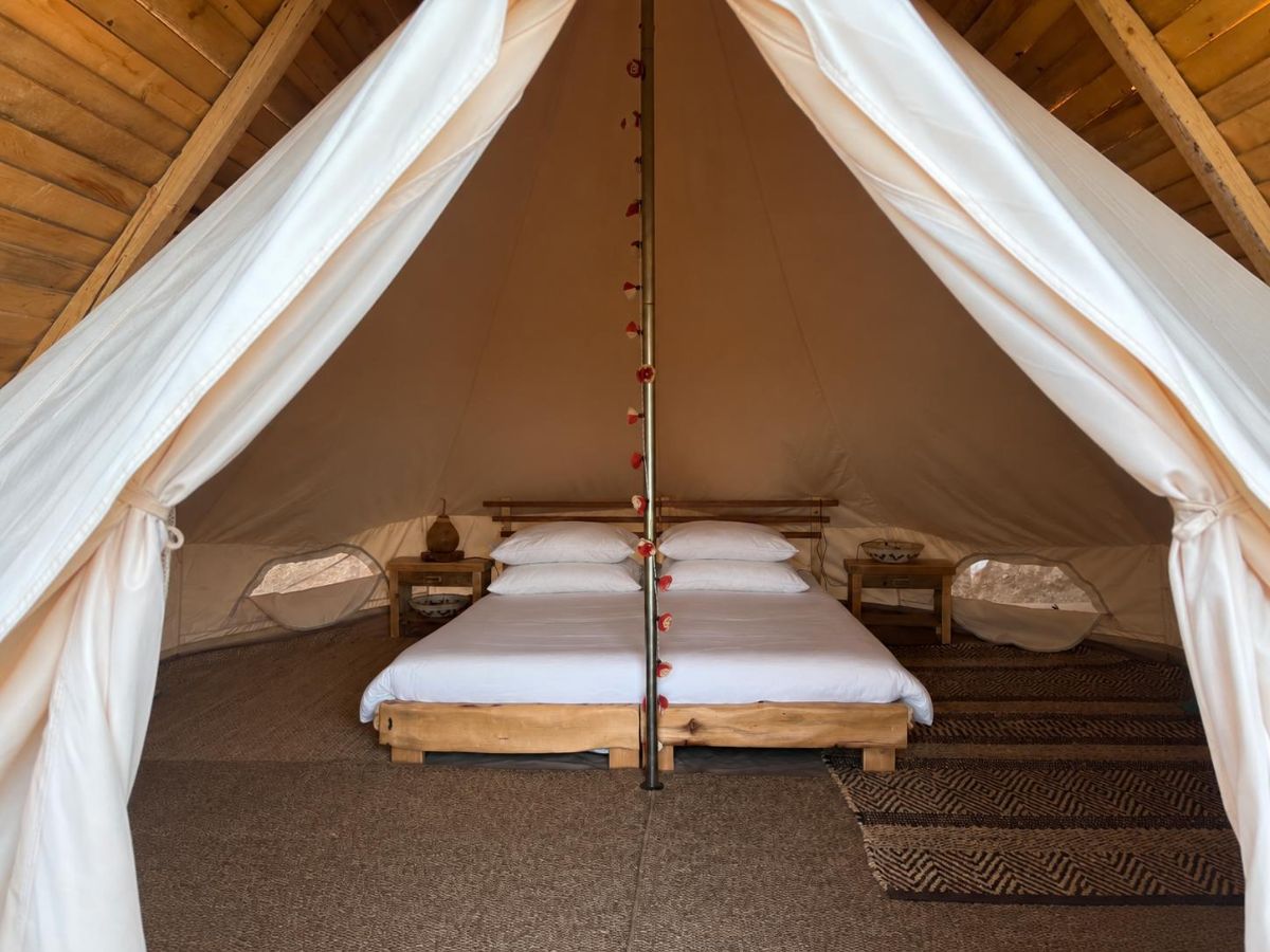 Inside a glamping tipi - made bed under the canvas