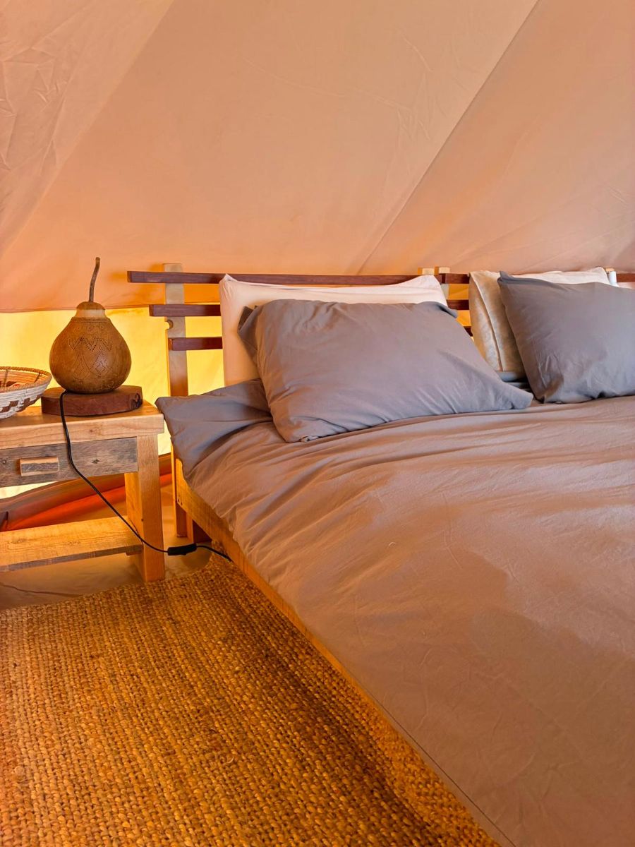 Bedside lamp and linens in the tipi at dusk